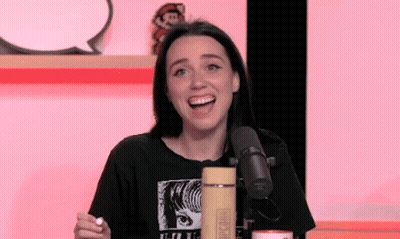 A Woman Is Sitting In Front Of A Microphone With Her Mouth Open And Smiling . GIF