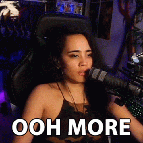 A Woman Is Sitting In Front Of A Microphone With The Words Ooh More Written On Her Face . GIF