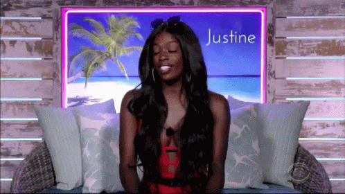 A Woman Is Sitting In Front Of A Sign That Says Justine On It GIF