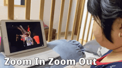 A Woman Is Sitting In Front Of A Tablet That Says Zoom In Zoom Out On The Bottom GIF