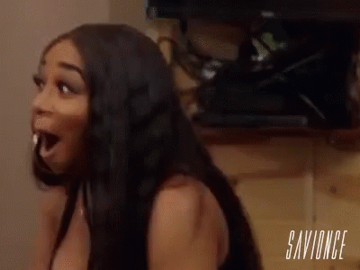 A Woman Is Sitting In Front Of A Television With Her Mouth Open And A Shocked Look On Her Face . GIF