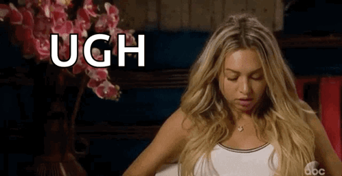 A Woman Is Sitting In Front Of A Vase Of Pink Flowers And The Word Ugh Is Written On The Screen . GIF
