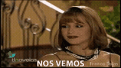 A Woman Is Sitting In Front Of A Wrought Iron Railing With The Words Nos Vemos On The Bottom GIF