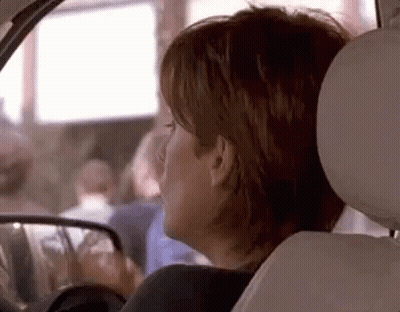 A Woman Is Sitting In The Back Seat Of A Car . GIF