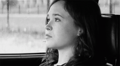 A Woman Is Sitting In The Back Seat Of A Car And Looking Out The Window . GIF