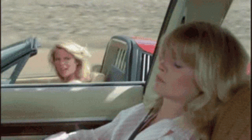 A Woman Is Sitting In The Back Seat Of A Car While Another Woman Is Driving . GIF