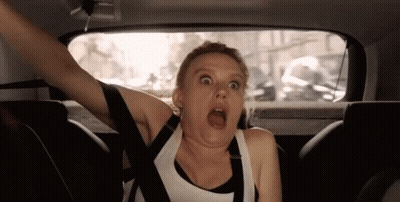 A Woman Is Sitting In The Back Seat Of A Car With Her Arms Outstretched And Making A Funny Face . GIF
