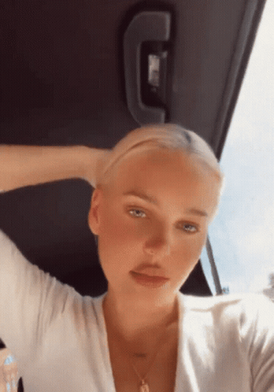 A Woman Is Sitting In The Back Seat Of A Car With Her Hand In Her Hair GIF