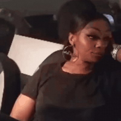 A Woman Is Sitting In The Back Seat Of A Car With Her Head Resting On Her Hand . GIF