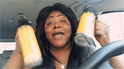 A Woman Is Sitting In The Driver 'S Seat Of A Car Holding A Can Of Soda . GIF