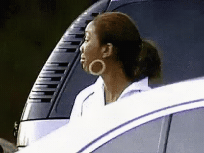 A Woman Is Sitting In The Driver 'S Seat Of A Car . GIF