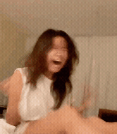 A Woman Is Sitting On A Bed And Laughing . GIF