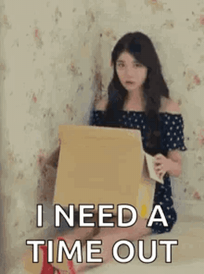 A Woman Is Sitting On A Bed Holding A Cardboard Box And A Piece Of Paper . GIF