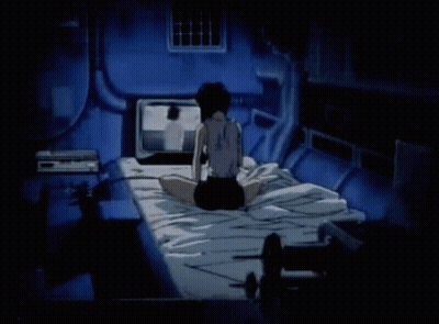 A Woman Is Sitting On A Bed In A Dark Room Watching A Television . GIF
