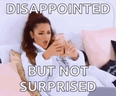 A Woman Is Sitting On A Bed Looking At Her Phone And Says Disappointed But Not Surprised . GIF