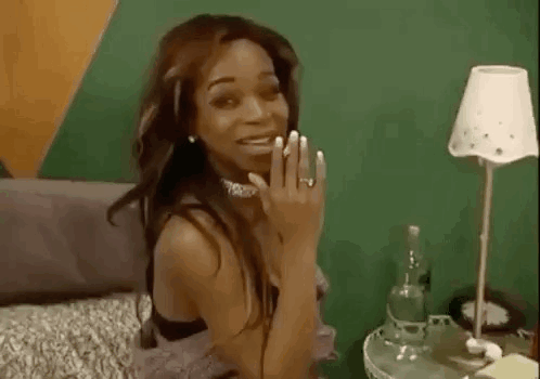 A Woman Is Sitting On A Bed With A Lamp And A Bottle Of Water . GIF