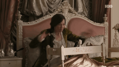 A Woman Is Sitting On A Bed With A Tray In Front Of Her That Says Hbo On The Bottom GIF