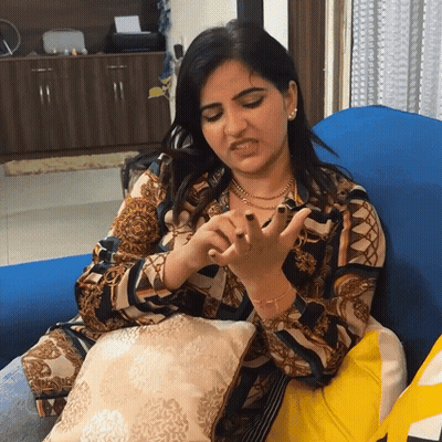 A Woman Is Sitting On A Blue Couch And Making A Face GIF