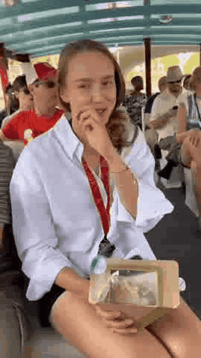 A Woman Is Sitting On A Boat Holding A Box Of Food And Covering Her Mouth . GIF
