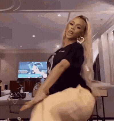 A Woman Is Sitting On A Chair In Front Of A Television And Dancing . GIF