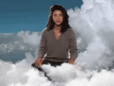 A Woman Is Sitting On A Cloud With A Blue Sky Behind Her GIF