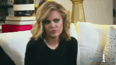 A Woman Is Sitting On A Couch And Making A Funny Face GIF