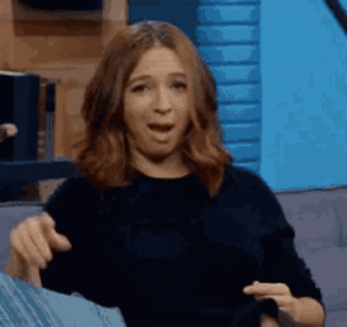 A Woman Is Sitting On A Couch And Pointing At Something . GIF