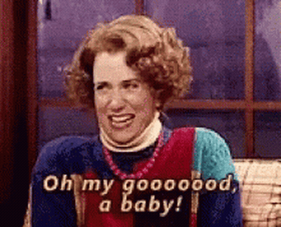 A Woman Is Sitting On A Couch And Smiling While Saying Oh My Goooood , A Baby . GIF