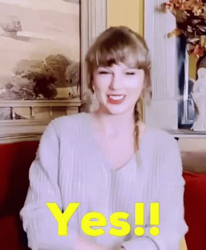 A Woman Is Sitting On A Couch And Smiling With The Word Yes Written In Yellow . GIF