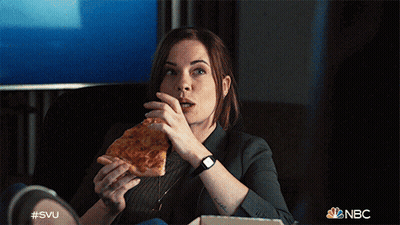 A Woman Is Sitting On A Couch Eating A Slice Of Pizza With A Nbc Logo In The Background GIF