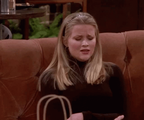 A Woman Is Sitting On A Couch Holding A Bag And Making A Funny Face GIF