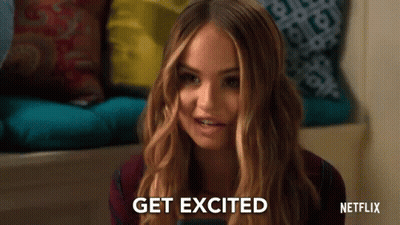 A Woman Is Sitting On A Couch Holding A Cell Phone And Smiling . GIF