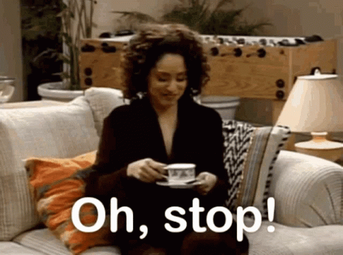 A Woman Is Sitting On A Couch Holding A Cup Of Coffee And Says Oh Stop . GIF