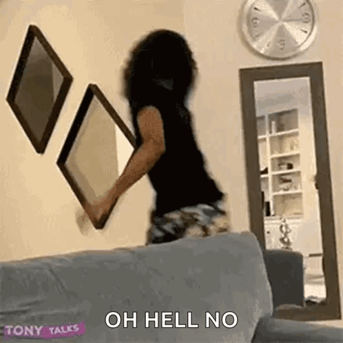 A Woman Is Sitting On A Couch Holding A Picture Frame And A Mirror . GIF