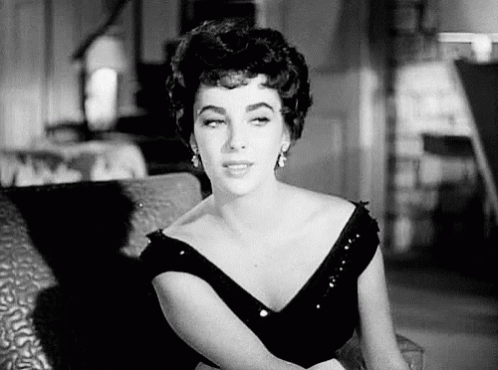 A Woman Is Sitting On A Couch In A Black And White Photo . GIF