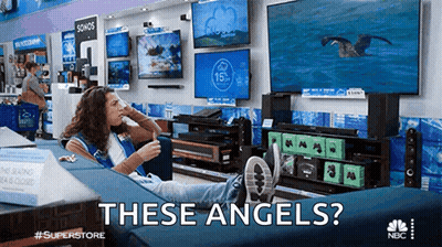 A Woman Is Sitting On A Couch In A Store With The Words " These Angels " Written Above Her GIF