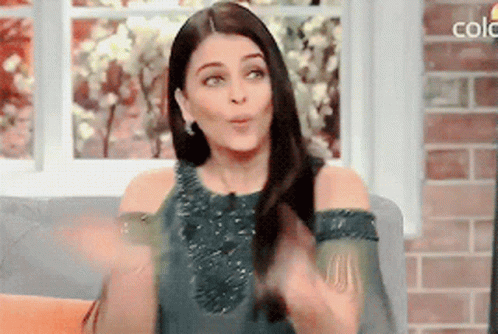 A Woman Is Sitting On A Couch In Front Of A Window With The Word Colo On The Bottom GIF