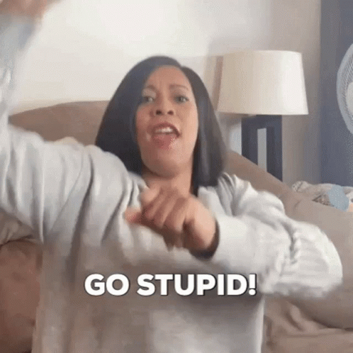 A Woman Is Sitting On A Couch Making A Funny Face And Saying `` Go Stupid ! '' GIF