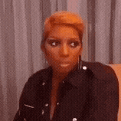 A Woman Is Sitting On A Couch Making A Funny Face . GIF