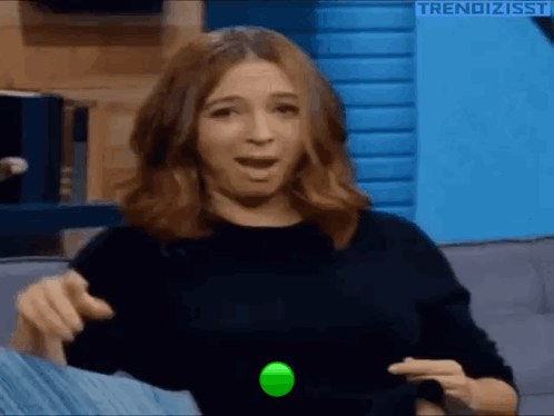 A Woman Is Sitting On A Couch Playing With A Green Ball . GIF