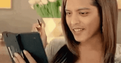 A Woman Is Sitting On A Couch Using A Tablet Computer While Holding A Pen . GIF