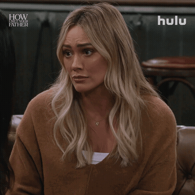 A Woman Is Sitting On A Couch With A Hulu Logo In The Background GIF