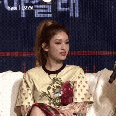 A Woman Is Sitting On A Couch With A Microphone In Her Hand And A Ponytail . GIF