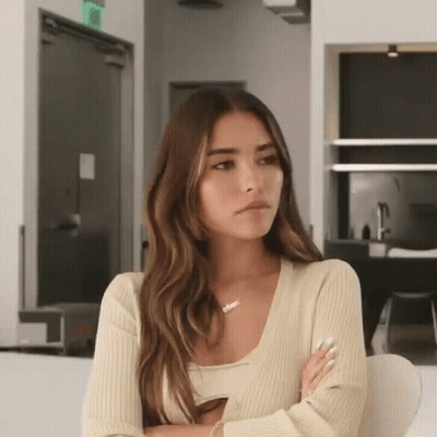 A Woman Is Sitting On A Couch With Her Arms Crossed . GIF