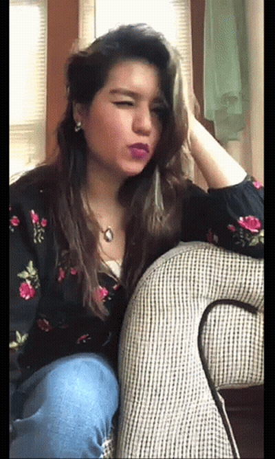 A Woman Is Sitting On A Couch With Her Eyes Closed GIF
