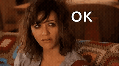 A Woman Is Sitting On A Couch With Her Hair Blowing In The Wind And The Words `` Ok Hot Mess '' Above Her . GIF