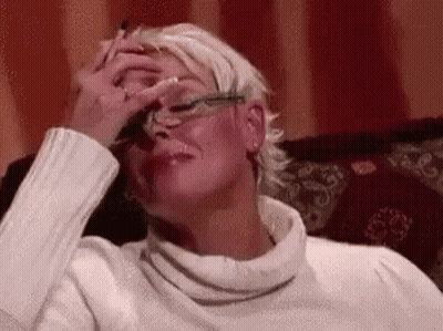 A Woman Is Sitting On A Couch With Her Hand On Her Forehead . GIF