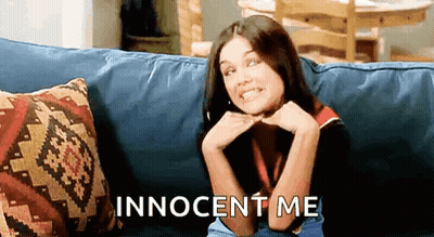 A Woman Is Sitting On A Couch With Her Hands On Her Chin And The Words Innocent Me Written On The Bottom . GIF