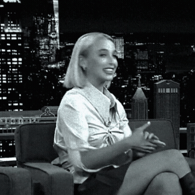 A Woman Is Sitting On A Couch With Her Legs Crossed GIF