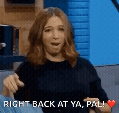 A Woman Is Sitting On A Couch With Her Mouth Open And Pointing At Something . GIF